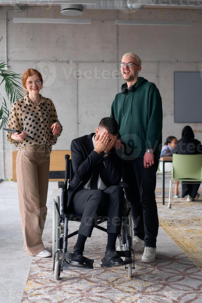 Group cheerful business colleagues, including a businessman in a wheelchair, posing together in a modern office, showcasing teamwork and inclusivity photo