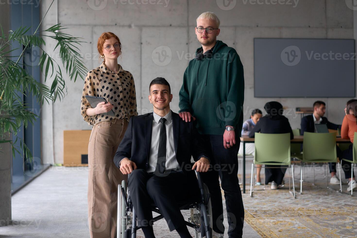 Group cheerful business colleagues, including a businessman in a wheelchair, posing together in a modern office, showcasing teamwork and inclusivity photo