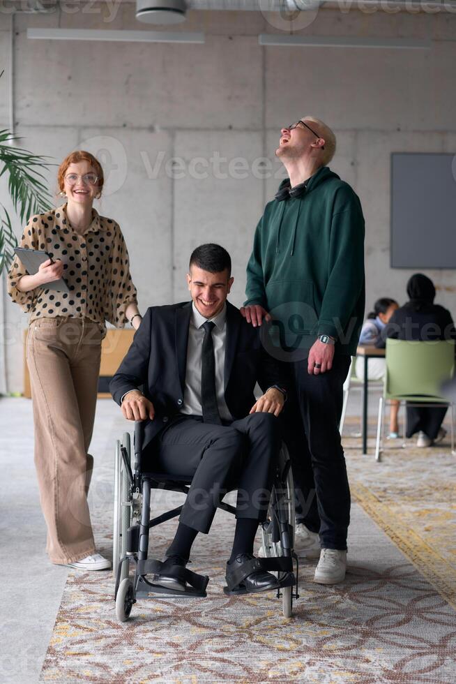 Group cheerful business colleagues, including a businessman in a wheelchair, posing together in a modern office, showcasing teamwork and inclusivity photo