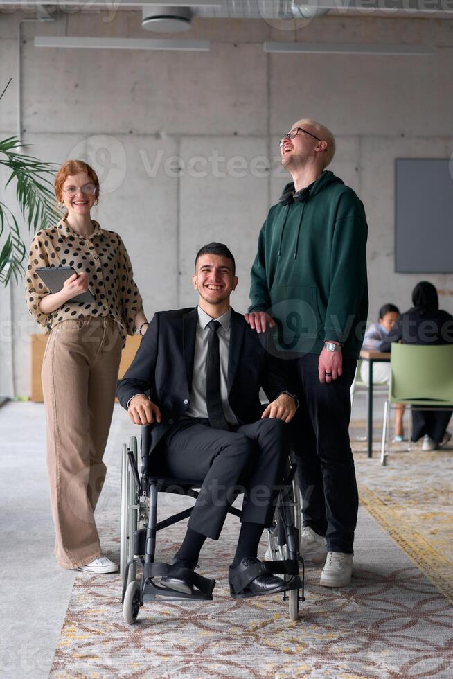 Group cheerful business colleagues, including a businessman in a wheelchair, posing together in a modern office, showcasing teamwork and inclusivity photo