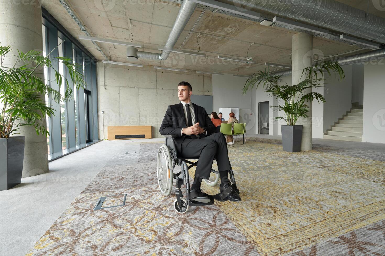 A director in a wheelchair sitting alone in an empty office, deeply reflecting on business strategies and decisions, contemplating the path forward with focused determination. photo