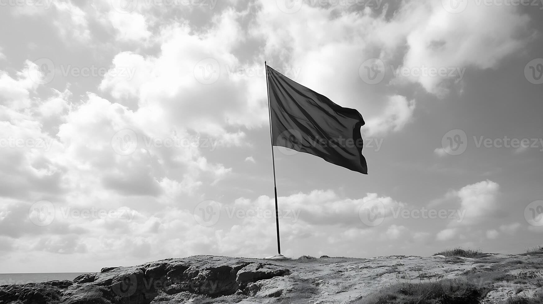 Solitary Flag on Rocky Landscape Under Dramatic Cloudy Sky in Black and White photo