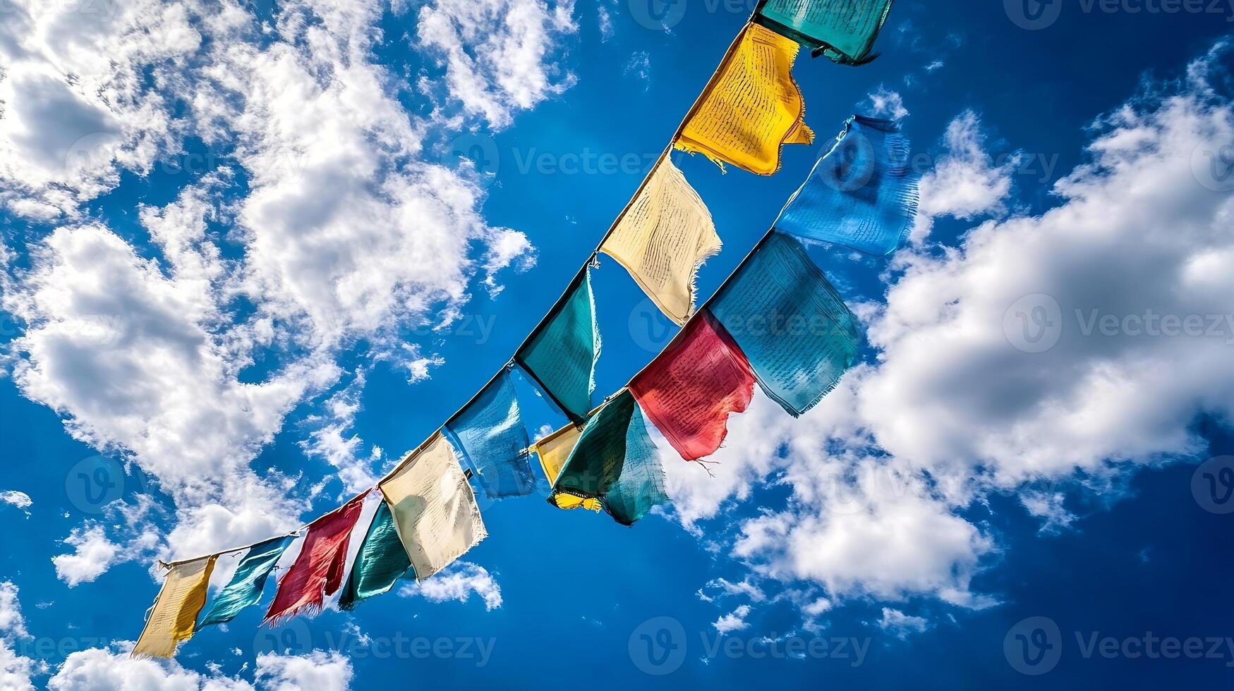Colorful Tibetan Prayer Flags Swaying in the Wind Against a Bright Blue Sky and Fluffy White Clouds photo