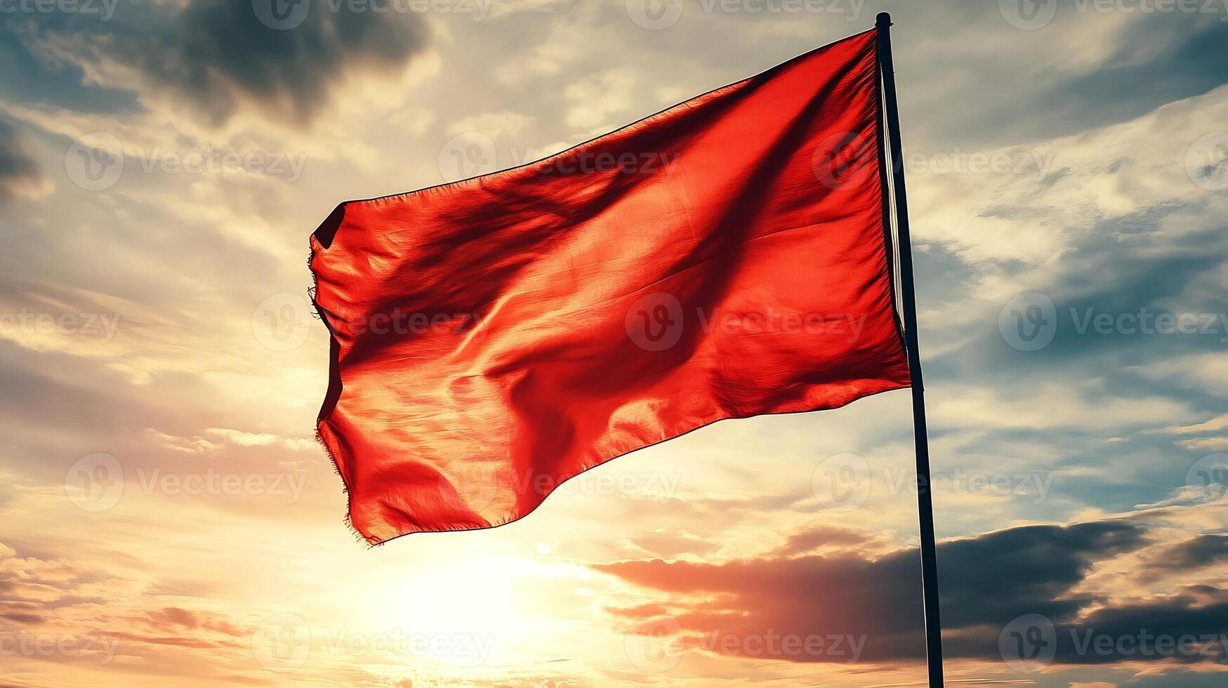 Red Flag on Pole Waving Against Dramatic Cloudy Sunset Sky for Symbolic and Motivational Themes photo