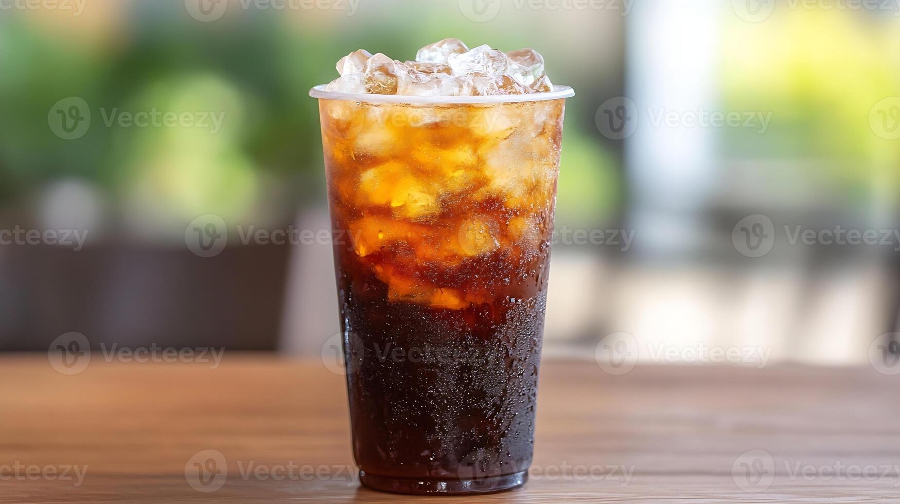 Chilled iced cola with condensation droplets on a clear cup in a bright outdoor setting photo