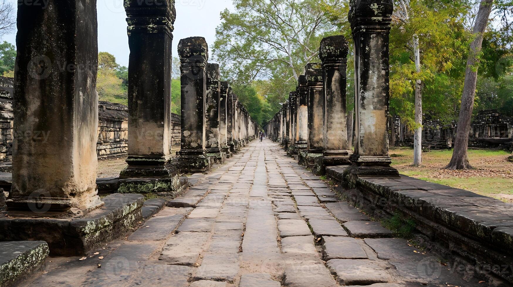 Ancient Stone Pillars and Pathway Leading Through Historical Temple Ruins Surrounded by Lush Green Trees and Nature photo