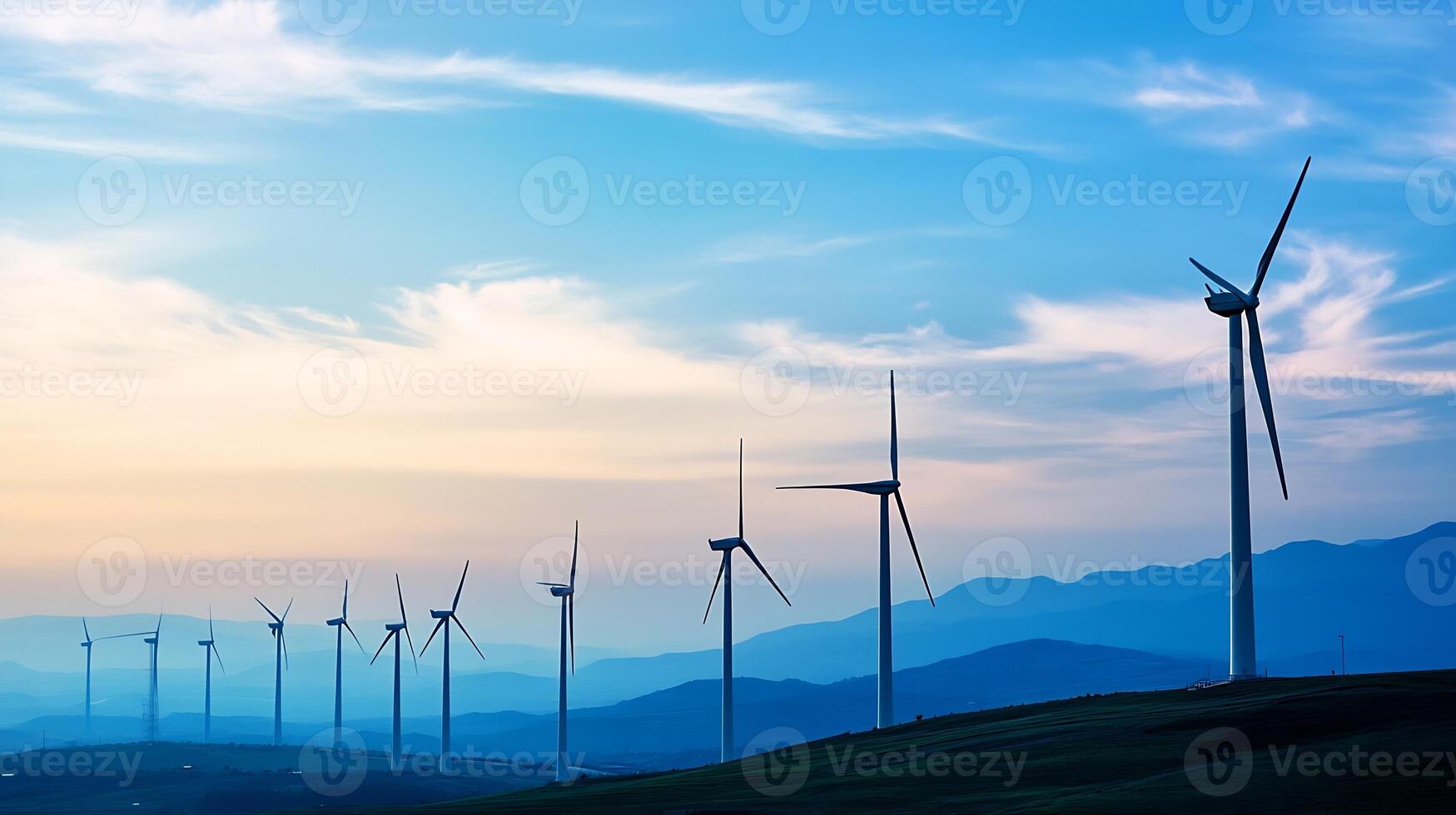 Panoramic view of wind turbines on a green hillside at dusk with vibrant blue sky photo