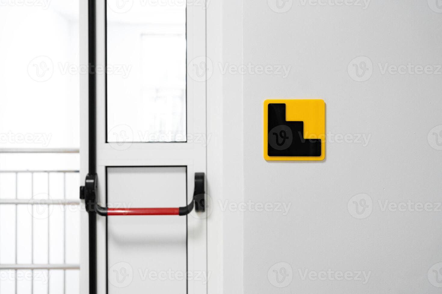 Door with a handle and a directional sign indicating stairs in a modern building interior photo