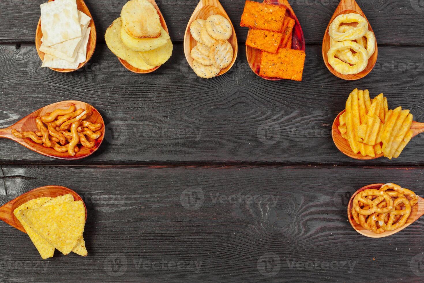 Mix of snacks . pretzels , crackers , chips and nachos on the table photo