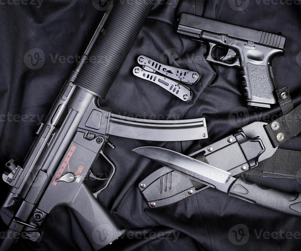 Rifle, gun, knife with sheath, compass and notebook with pen on on black cloth photo