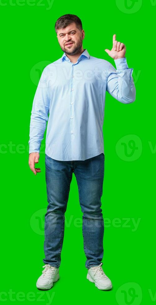 A man with a friendly smile gestures upwards while wearing a navy shirt against a bright green background photo
