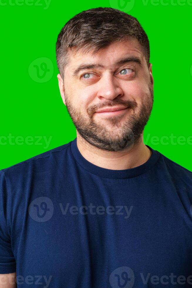 A young man smiles playfully against a bright green backdrop, showcasing a cheerful expression photo