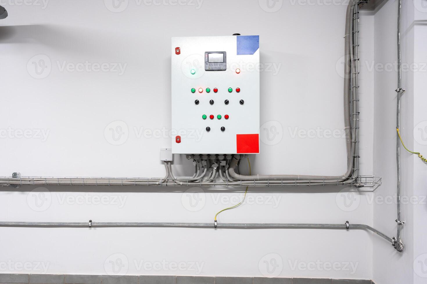 Control panel mounted on a wall with various indicator lights and buttons in an industrial setting photo