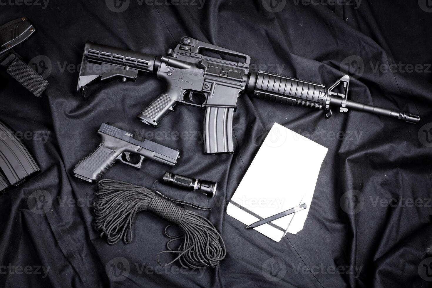 Rifle, gun, knife with sheath, compass and notebook with pen on on black cloth photo