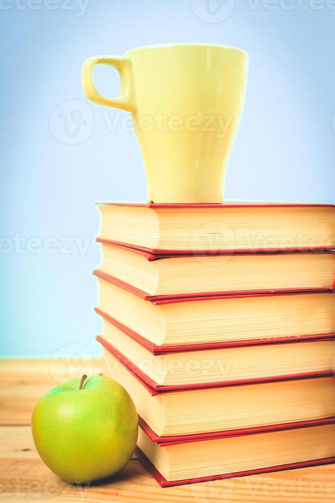 Color cup of tea with books on table photo