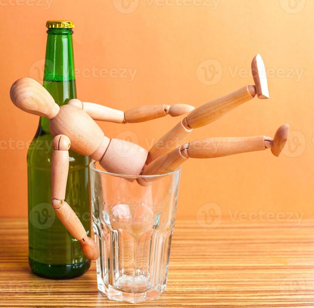 Alcoholism concept. Wooden doll with Alcohol drink photo