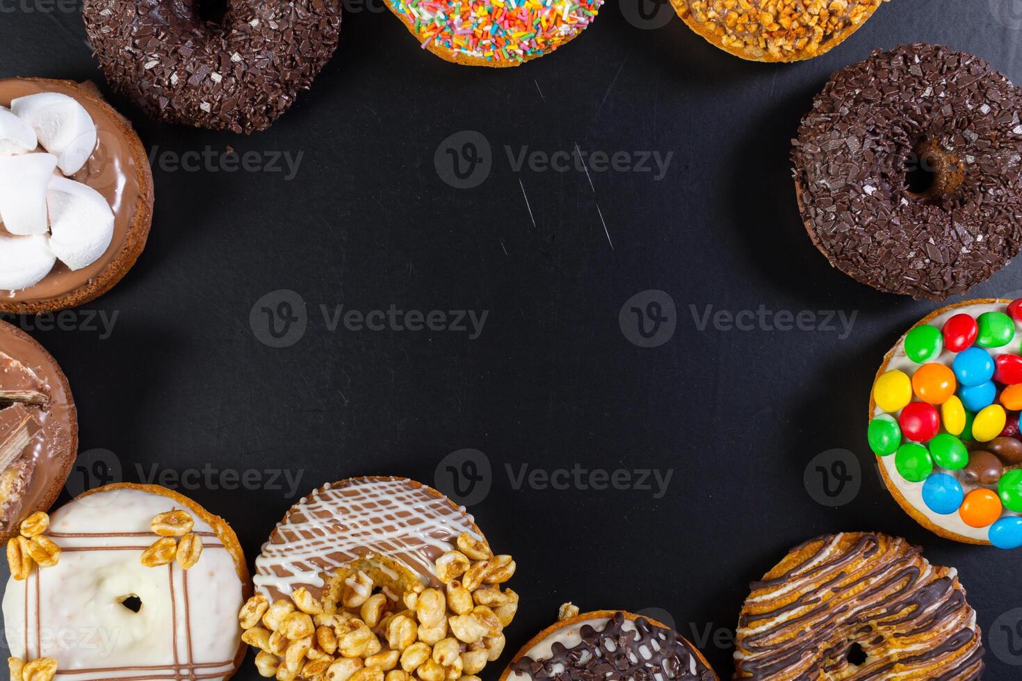 Assorted donuts from above on black background photo