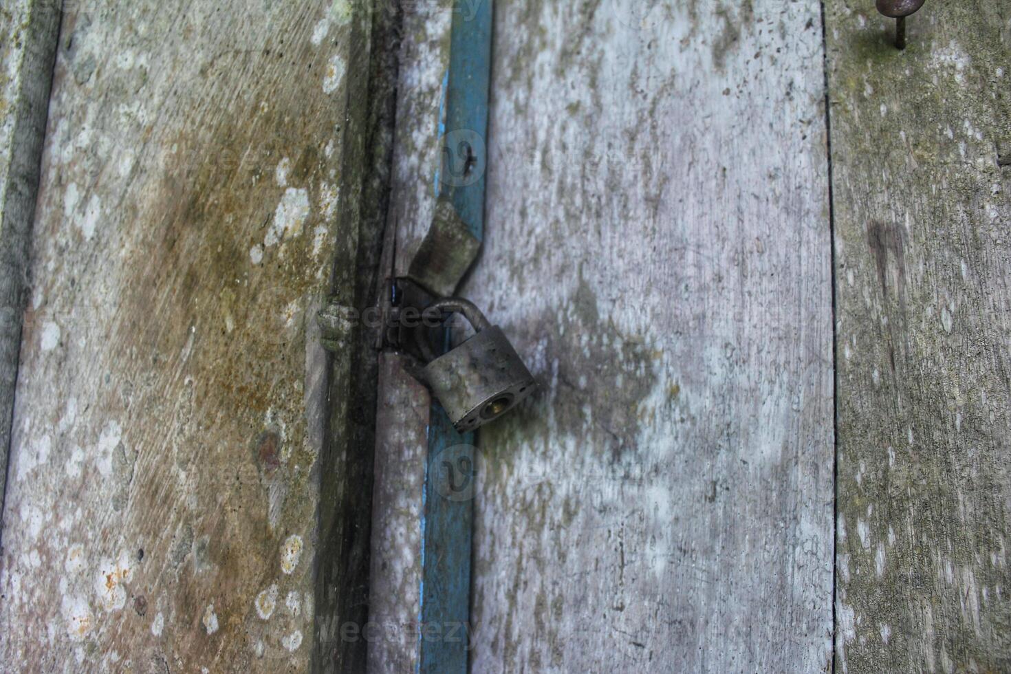 a door that is locked using a old padlock made of iron, building security photo