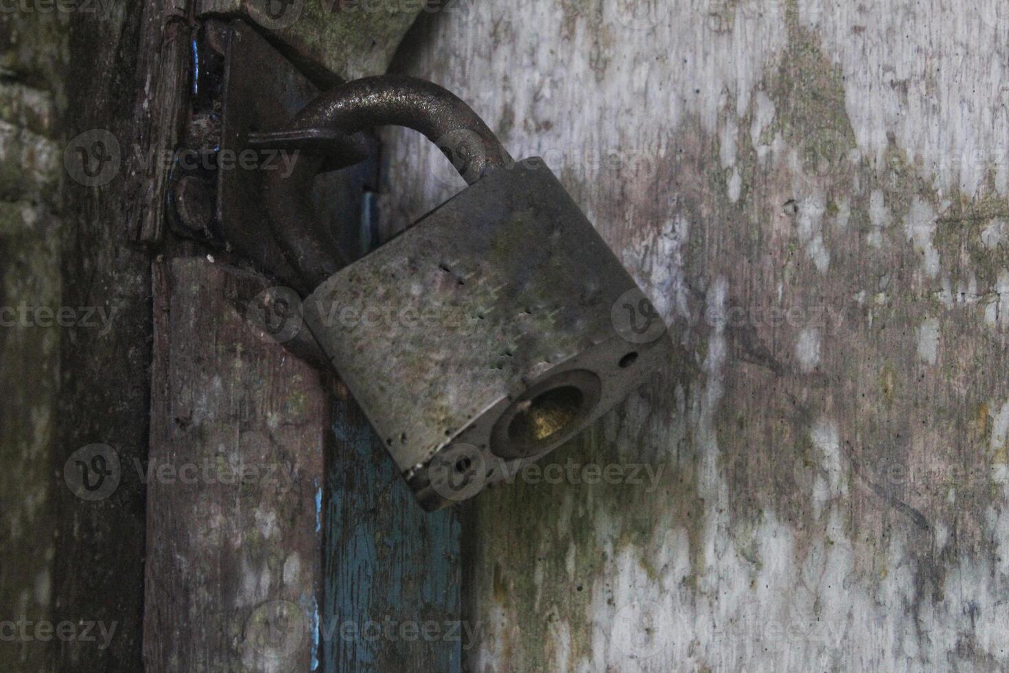 a door that is locked using a old padlock made of iron photo