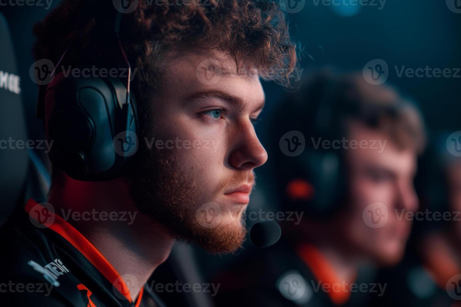 Concentrating intently, a young esports player with headphones engages in a competitive match, showcasing his dedication at a prominent gaming tournament. photo
