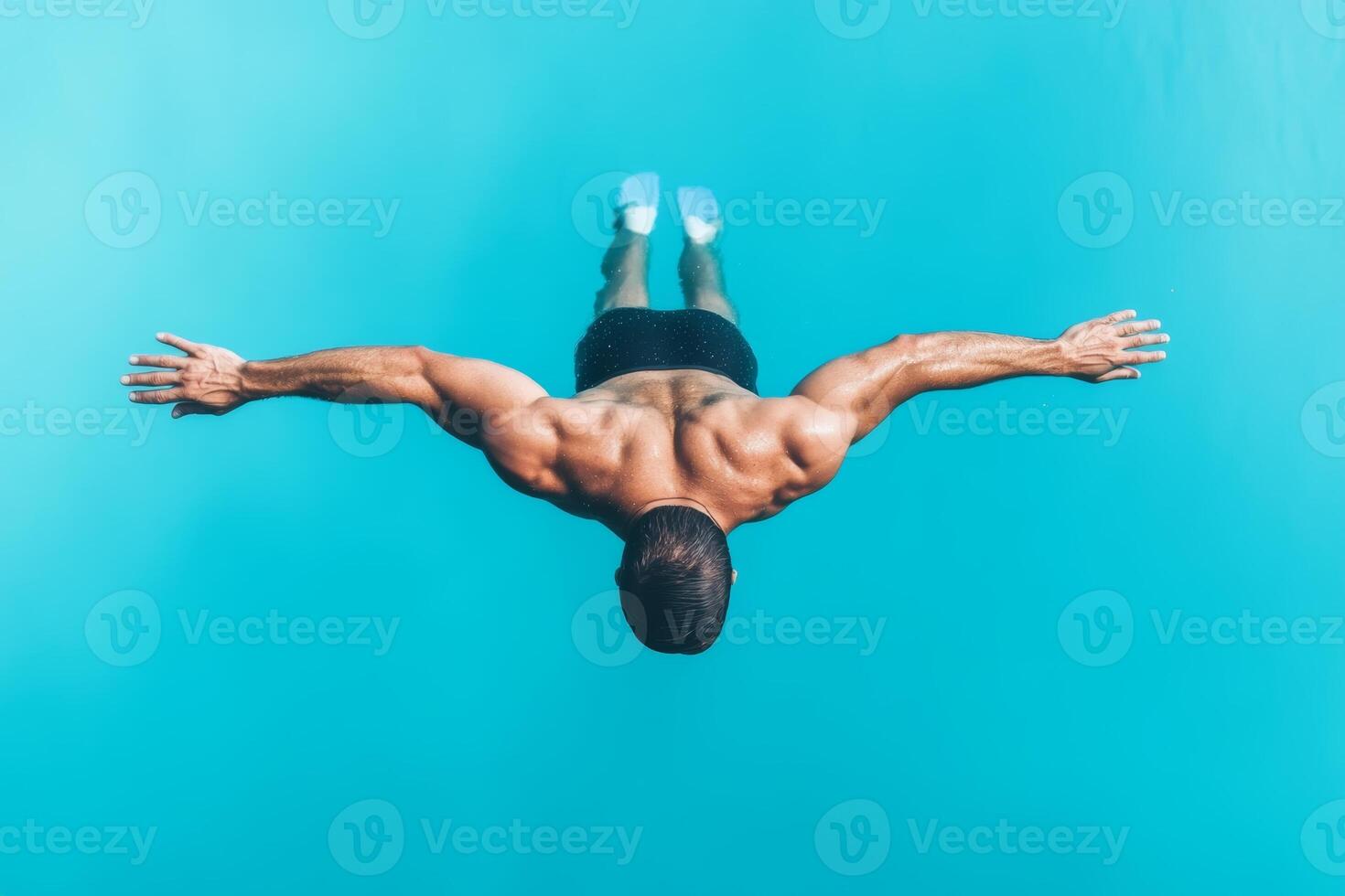 A man dives into clear blue water with arms extended, showcasing athleticism and grace during a warm summer day photo