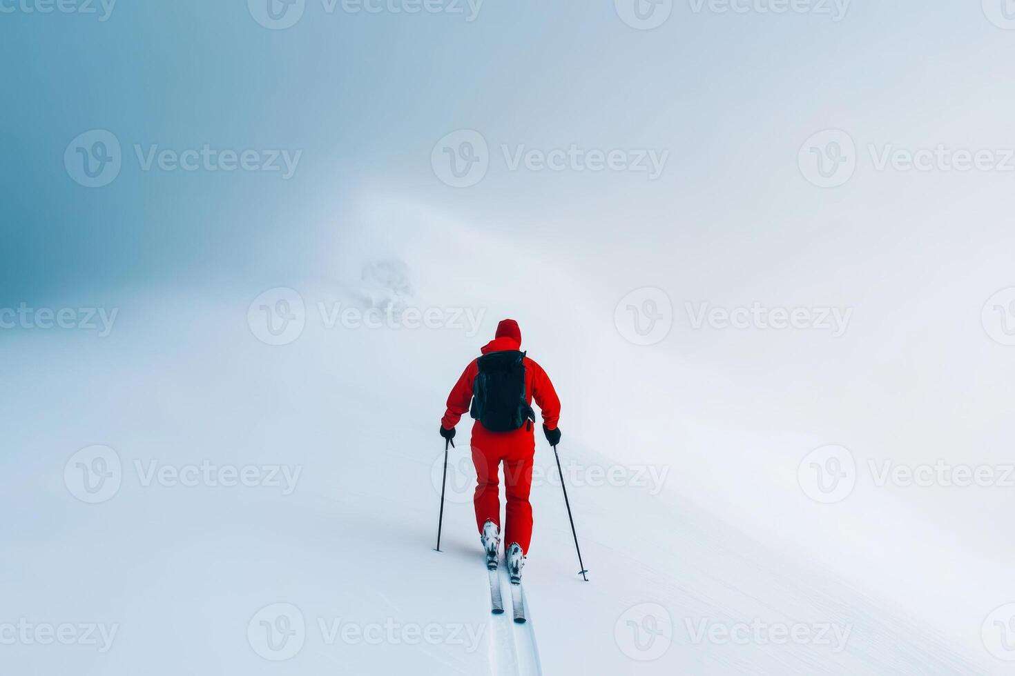 A skier navigates through fog-covered snowy terrain during winter in a remote mountainous region photo