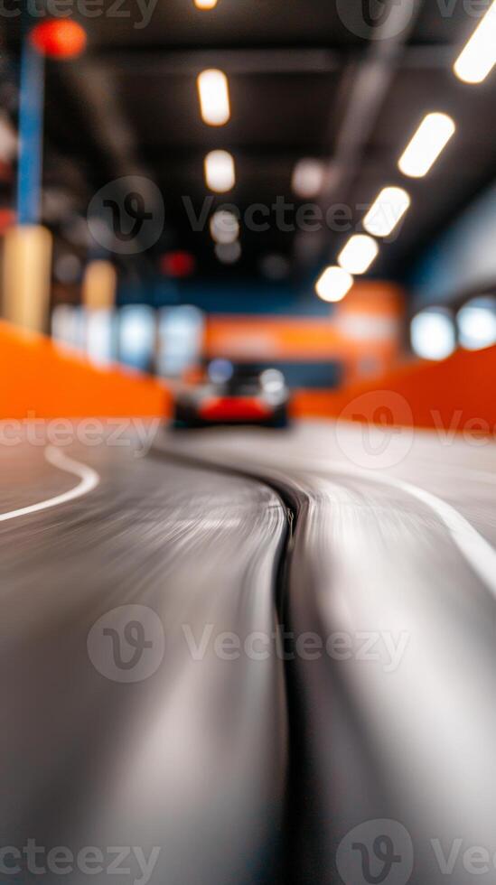 A close-up view of a racing track with a blurred toy car speeding by in an indoor raceway photo