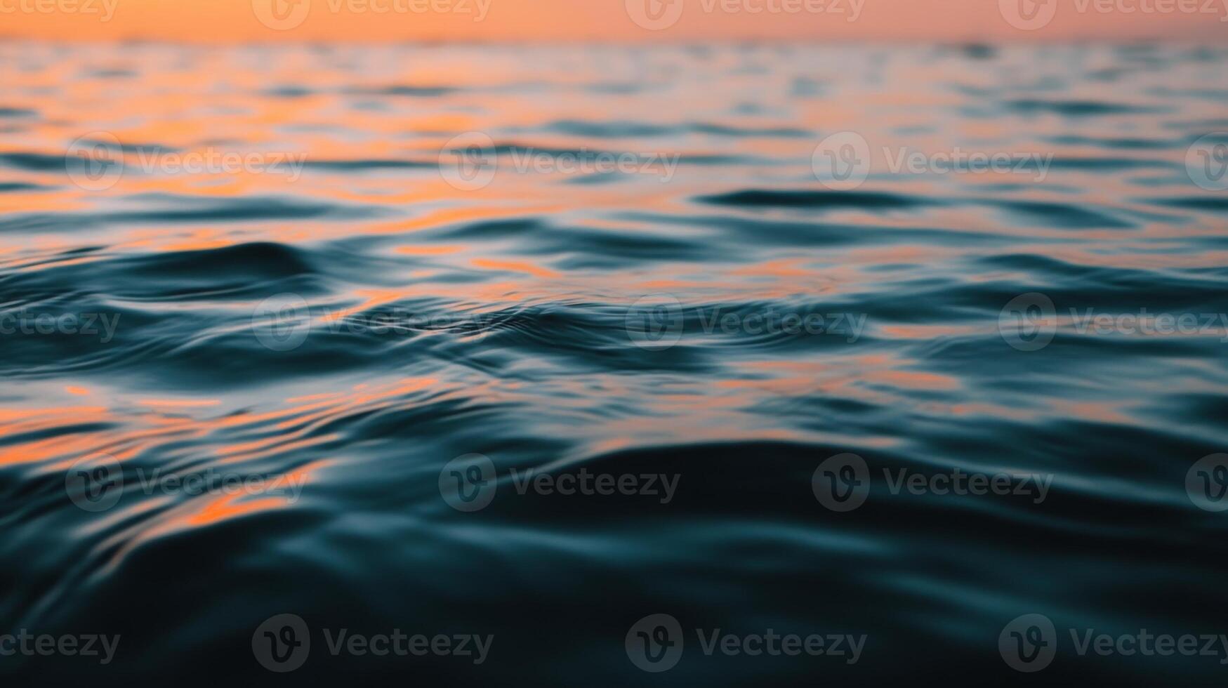Calm ocean waves reflecting the warm colors of sunset on a tranquil evening at sea photo