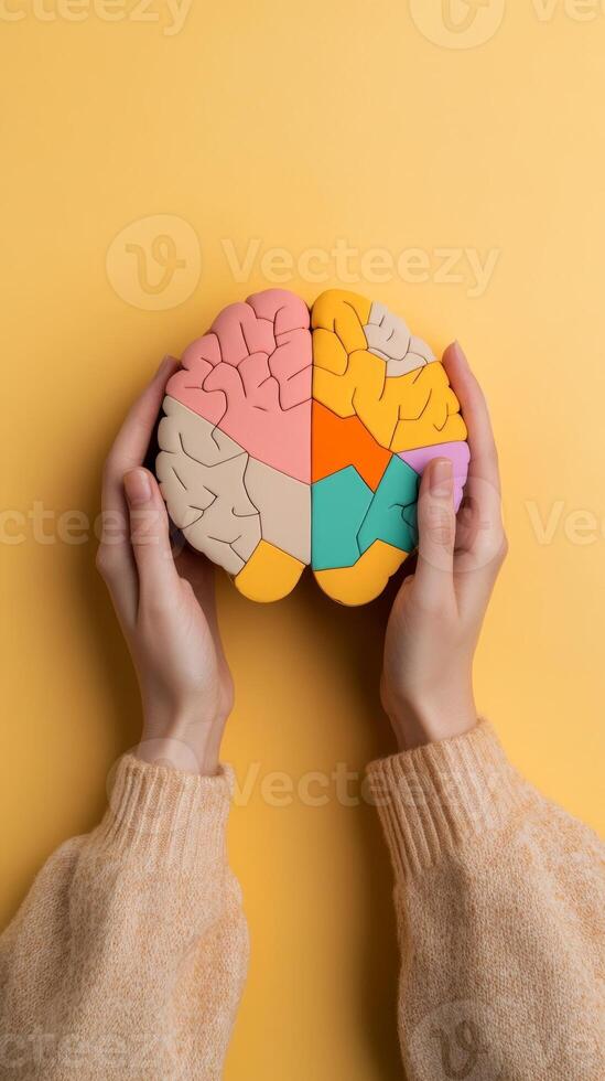 Hands holding a colorful brain model against a yellow background, symbolizing creativity and cognitive function photo