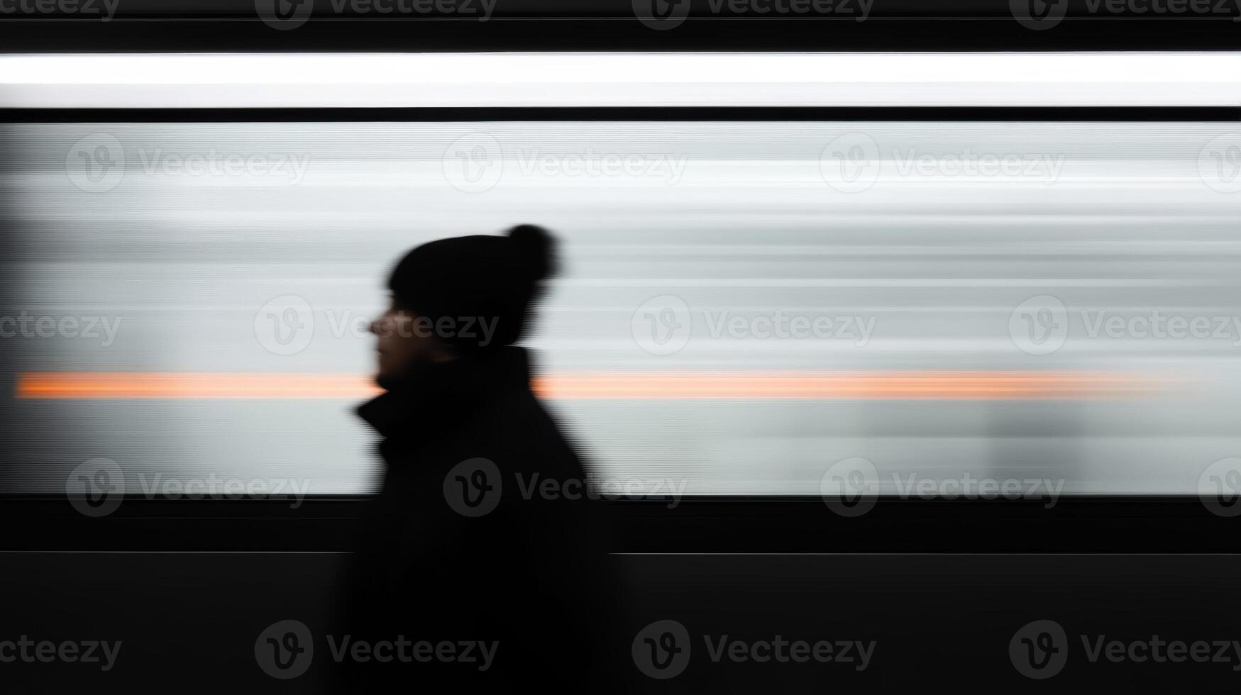 A person walking past a speeding train at a subway station on a chilly day in the city during the morning rush hour photo