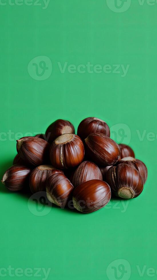 A Bountiful Heap of Hazelnuts on a Vibrant Green Background photo