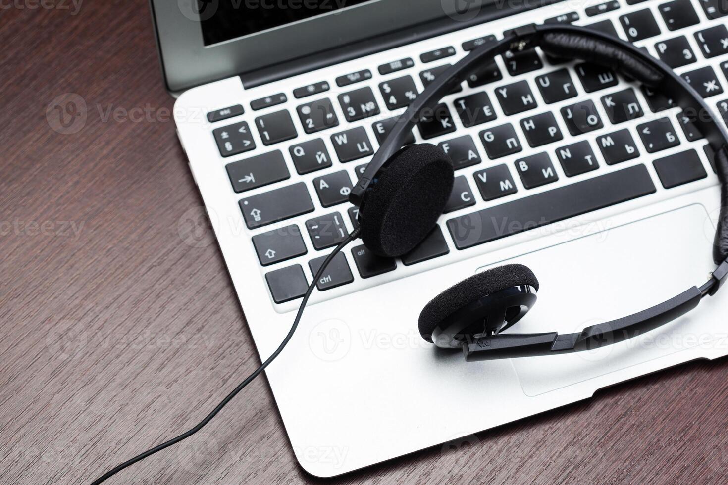 Headphones with laptop on table close up photo