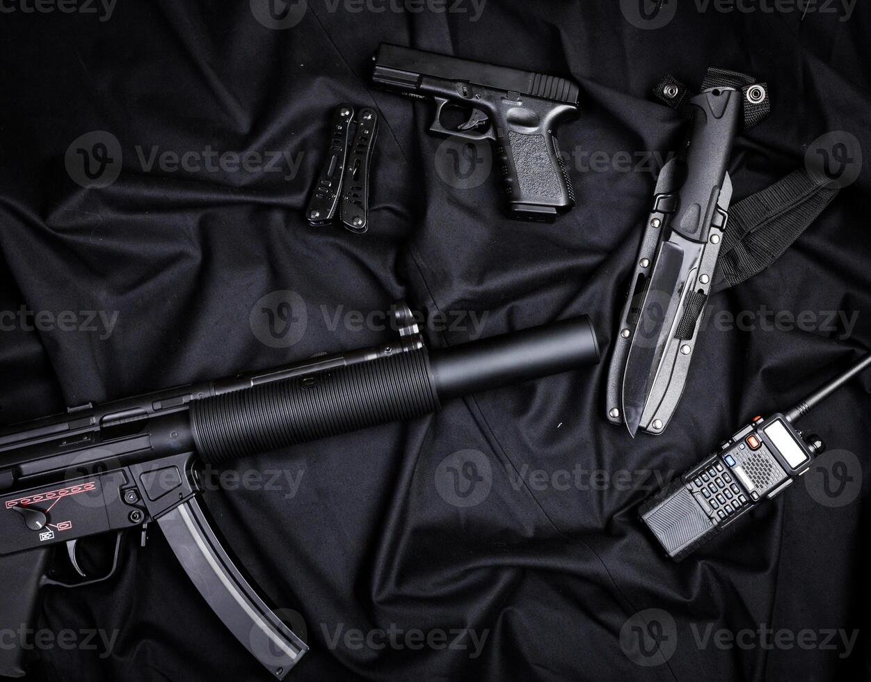 Rifle, gun, knife with sheath, compass and notebook with pen on on black cloth photo