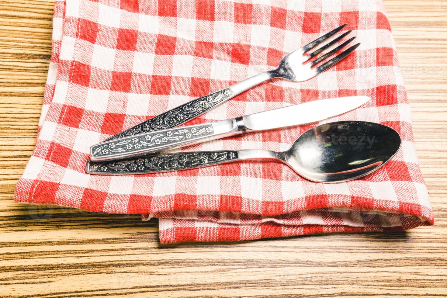 Fork and table knife on red gingham tablecloth photo