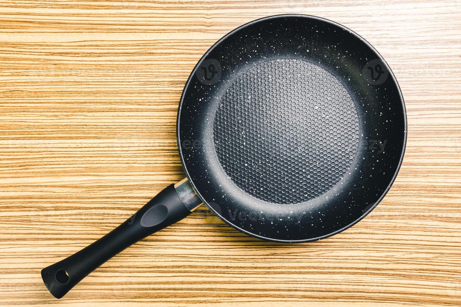 Frying pan on wooden table background. View from above photo