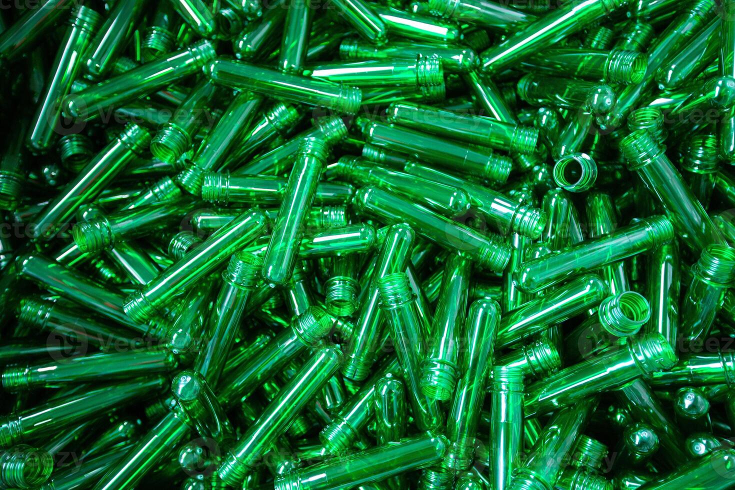 Collection of transparent green plastic tubes arranged randomly in a heap on a surface photo