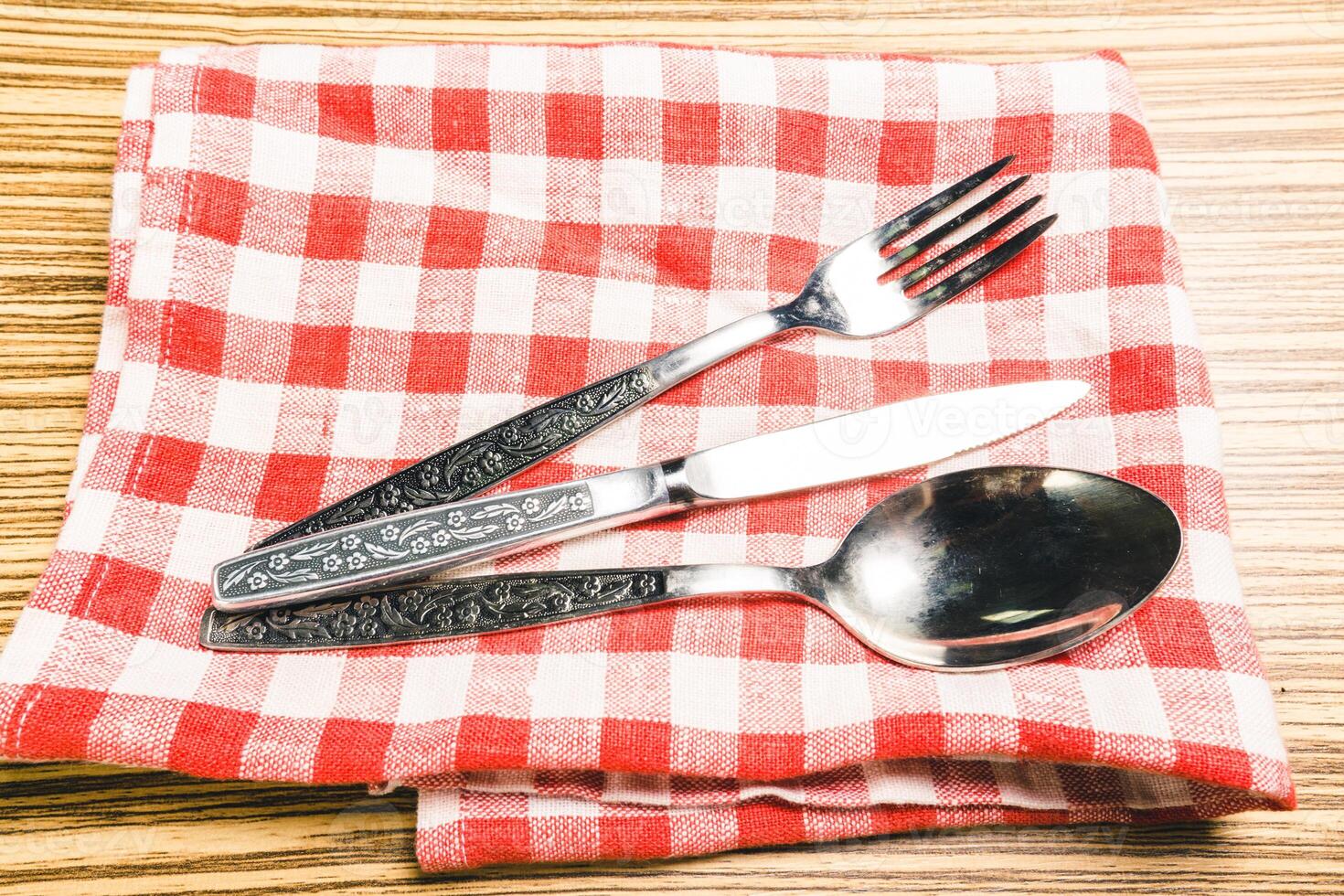 Fork and table knife on red gingham tablecloth photo