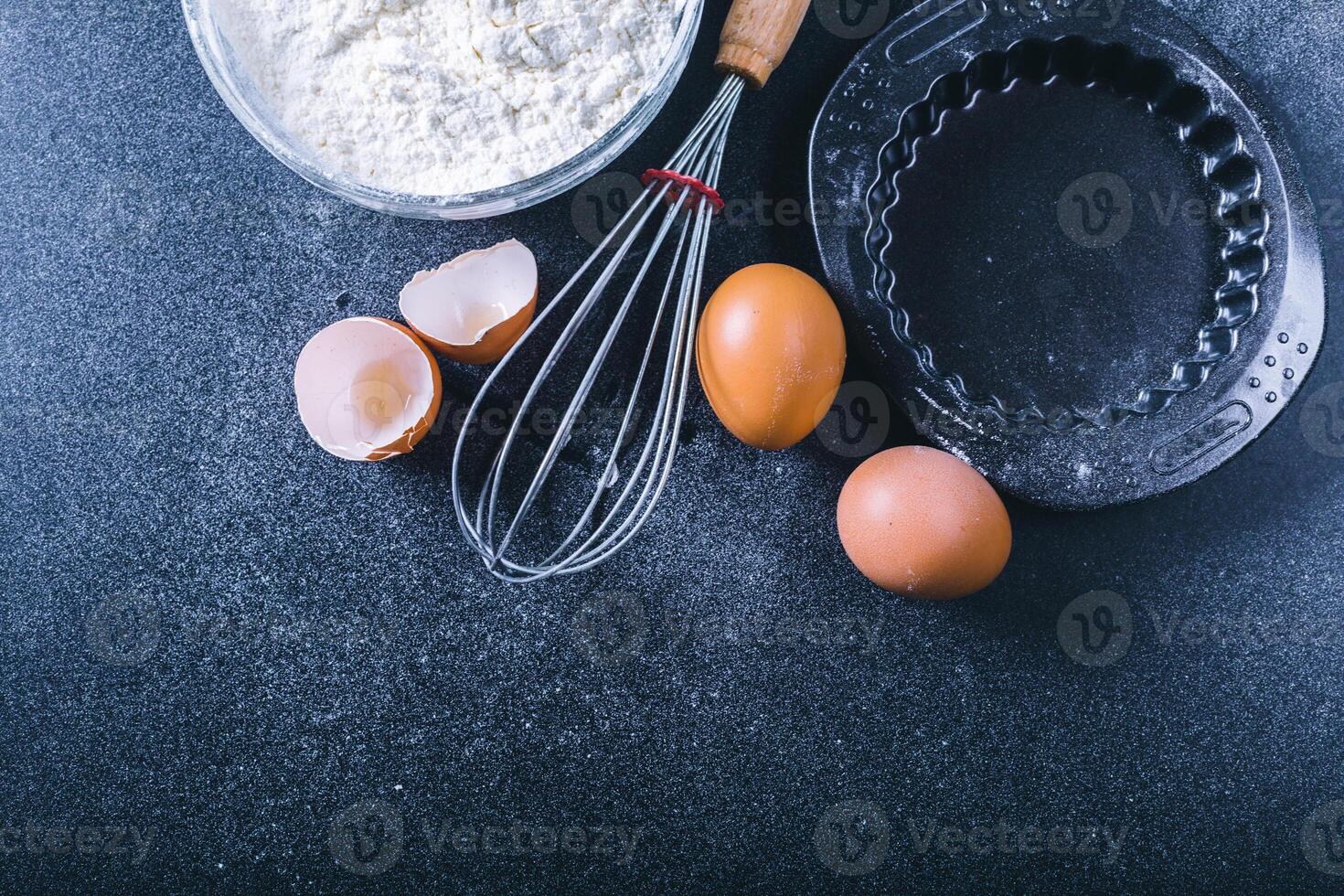 Baking dark background with blank cook book, eggshell, bread, flour, rolling pin. Ingredients for the baking. photo