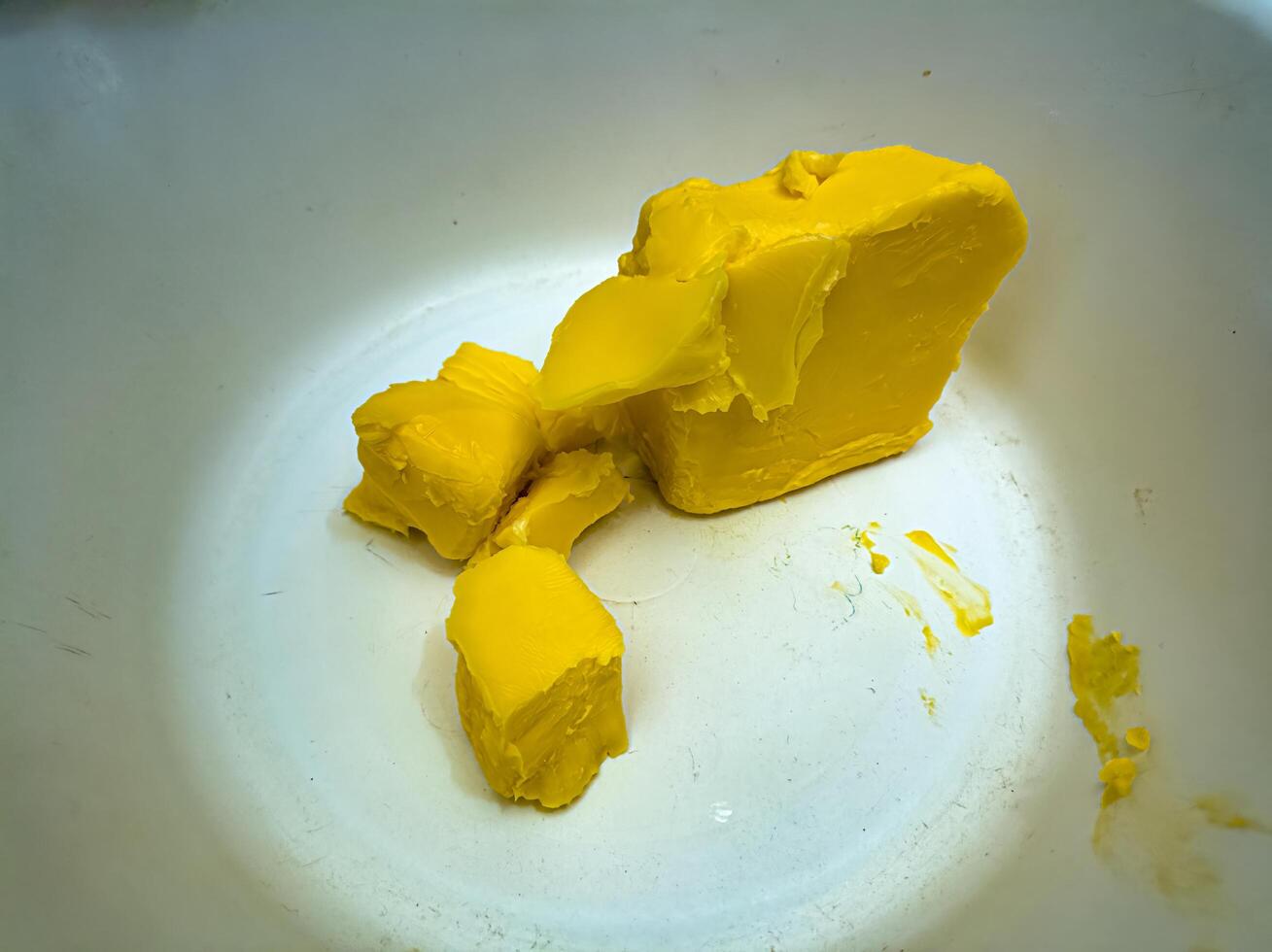 A close up of a chunk of yellow butter in a white bowl, showcasing its smooth texture and vibrant color, perfect for culinary and food related themes photo