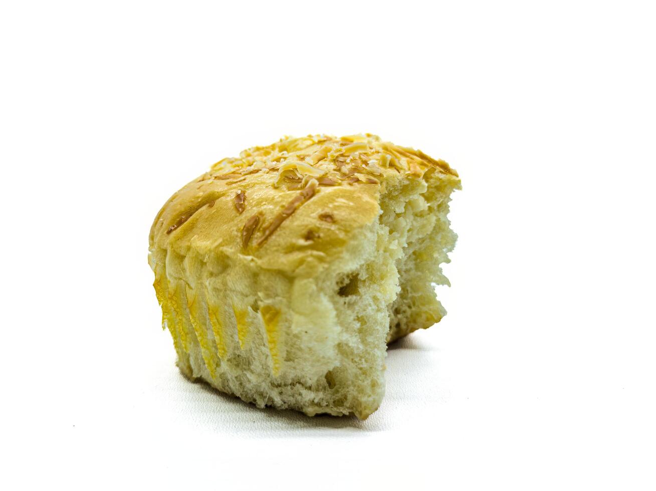 A close up of a partially eaten bread roll with a golden crust and sprinkled with cheese, isolated on a white background photo