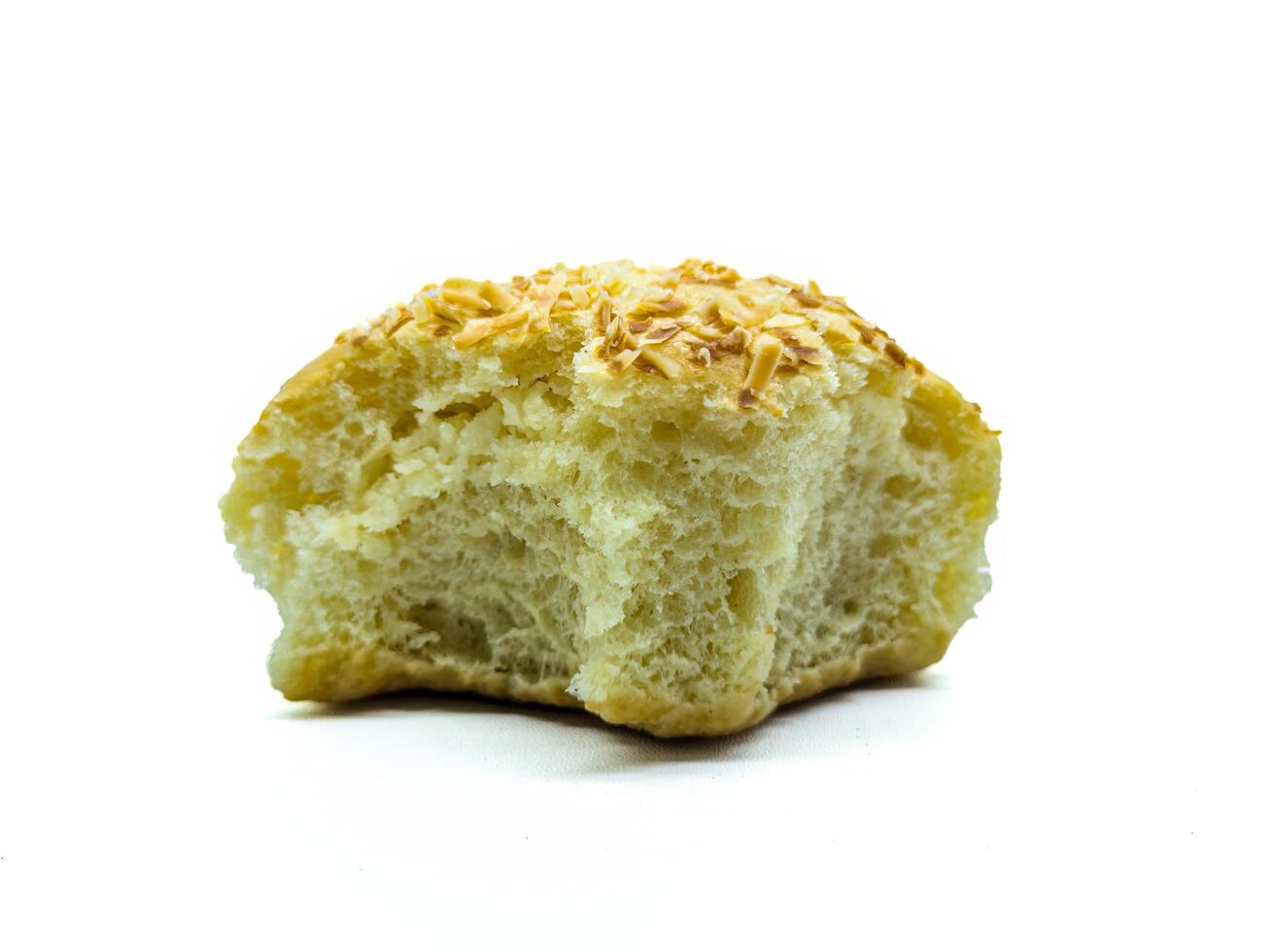 A close up of a partially eaten bread roll topped with shredded cheese. The texture of the bread is soft and fluffy, with a golden-brown crust photo