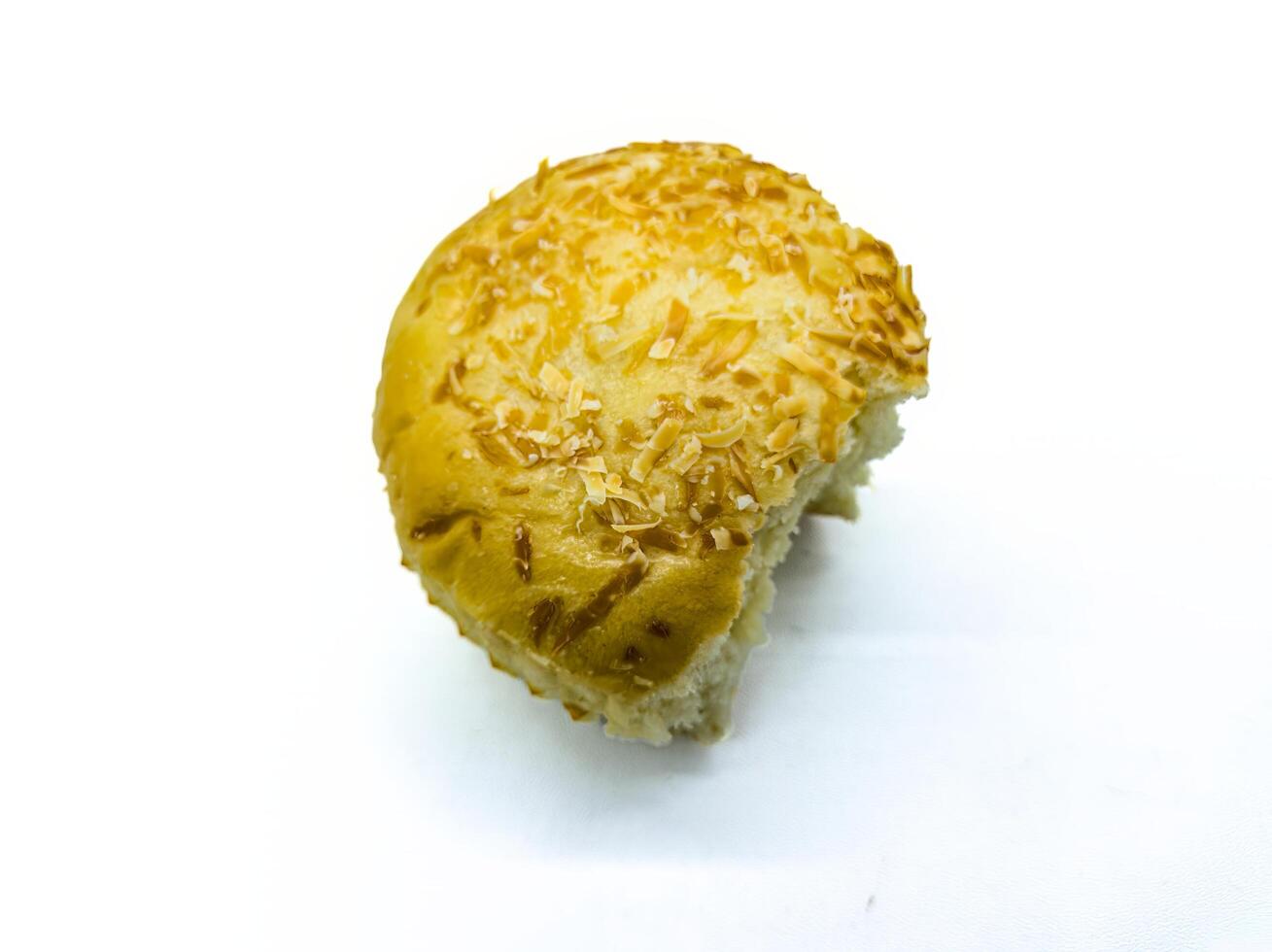 A partially eaten, golden brown bun topped with shredded cheese on a white background. The bite reveals the soft, fluffy texture inside, making it look appetizing photo