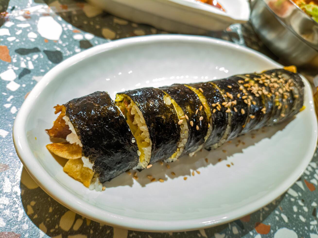 A close up of a delicious gimbap roll on a white plate, showcasing its vibrant ingredients and sesame seed topping, perfect for food enthusiasts and culinary photography photo