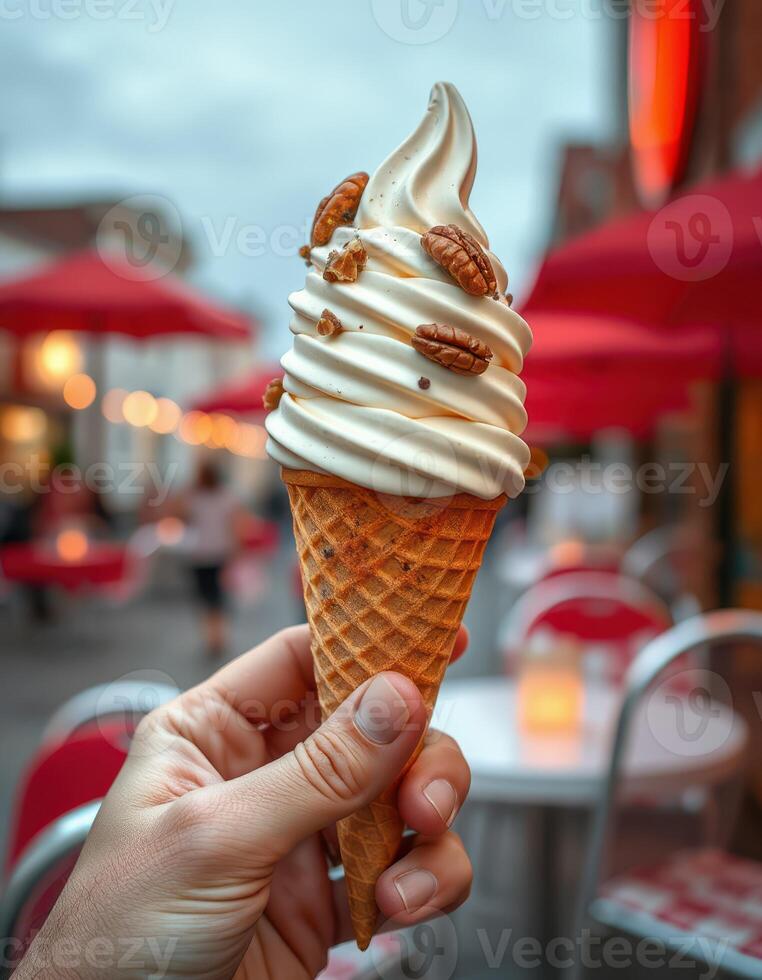 Enjoying a delicious soft serve ice cream cone topped with nuts at an outdoor cafe on a cloudy day photo