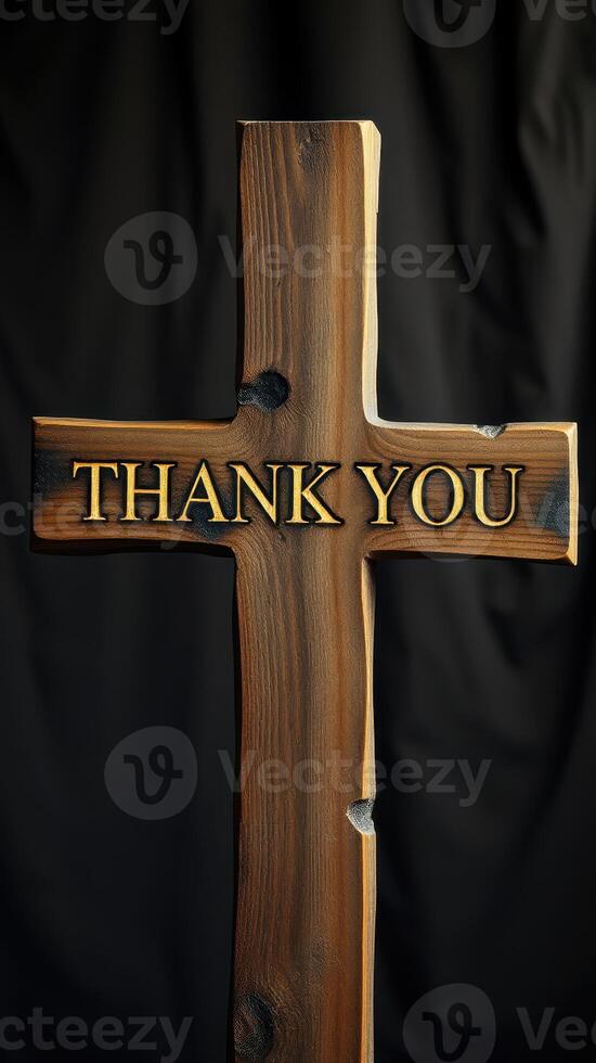 Wooden cross with an engraved message expressing gratitude against a dark background photo