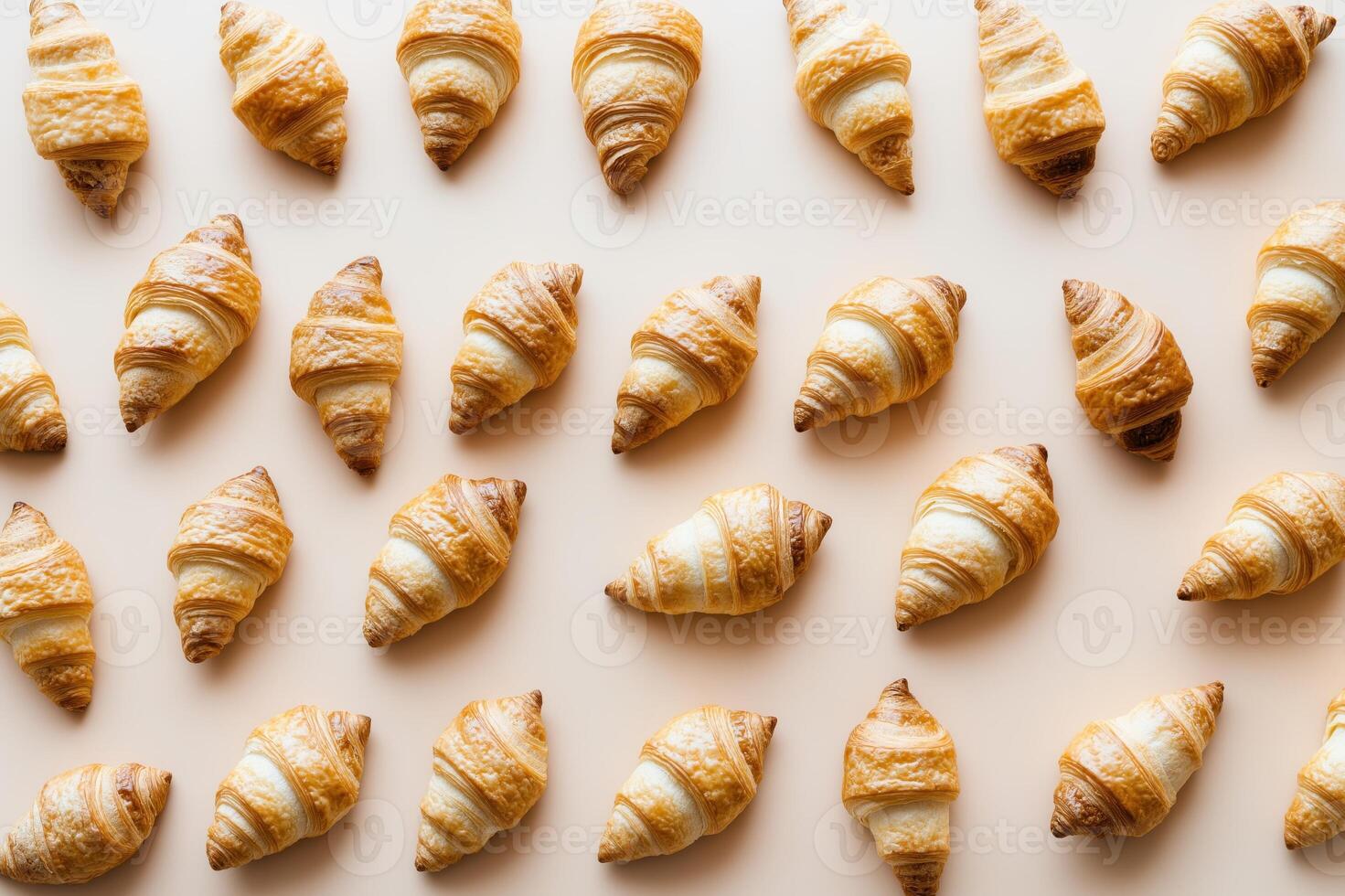 Fresh croissants arranged beautifully on a pastel peach background, emphasizing their flaky layers and golden crusts for bakery and breakfast themes photo