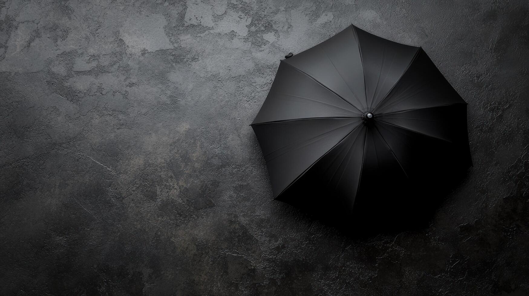 Black umbrella placed on a textured surface creating a stark visual contrast in a minimalist setting photo