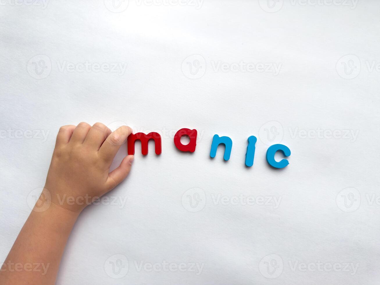 Childs hand arranging colorful letter manic letters on white background photo