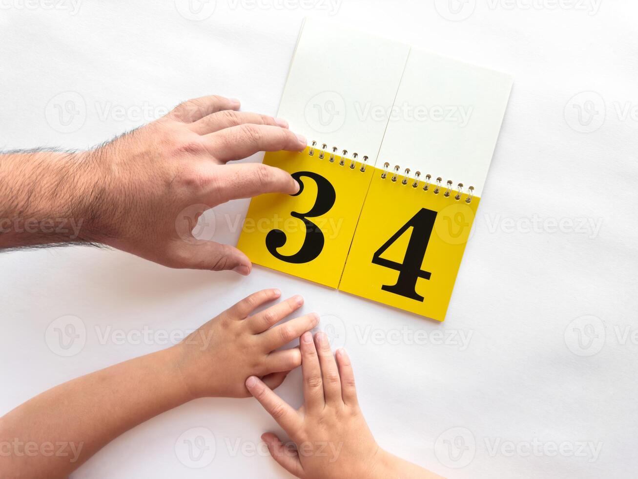 Father and child turn over page of calendar with large numbers photo