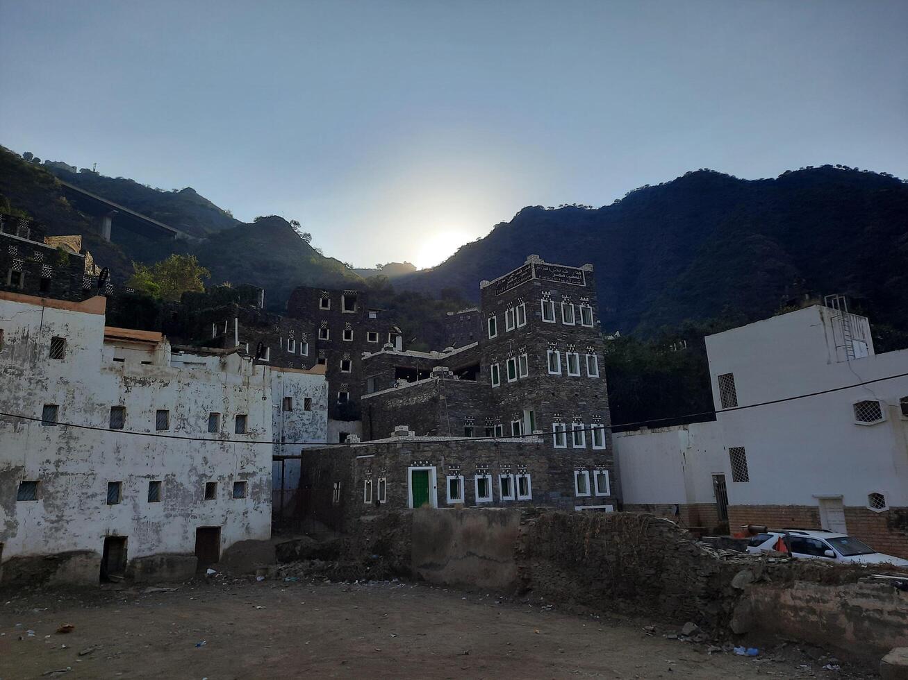 Asir, Saudi Arabia, 03 Jan 2025 - A beautiful daytime scene showcasing the historic structures of Rijal Almaa archaeology, with the sun rising behind the mountains in Asir. photo